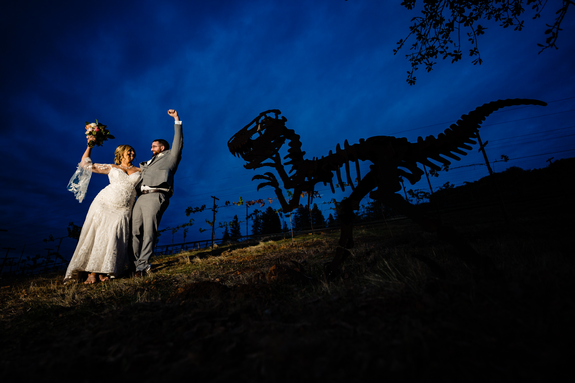 Wedding photo with dinosaur skeleton at night.